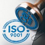 3D_illustration_of_a_rubber_stamp_with_the_text_ISO_9001_certification_over_paper_background.